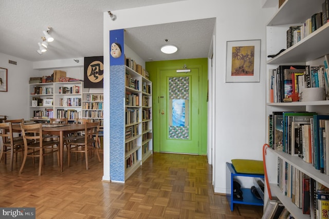 living area with a textured ceiling, bookshelves, and visible vents