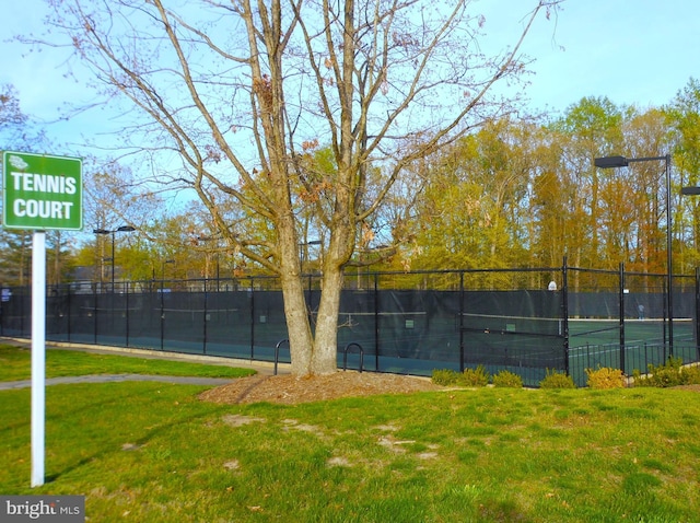 view of sport court featuring fence and a lawn