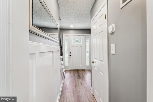 doorway with a textured ceiling and wood finished floors