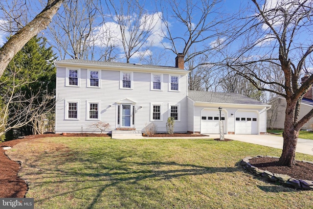 colonial house featuring a front yard, a garage, driveway, and a chimney