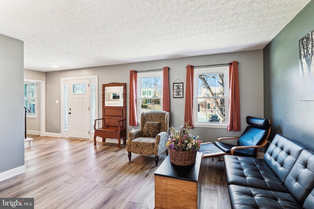 interior space with light wood finished floors, baseboards, and a textured ceiling