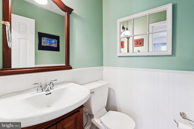 bathroom with toilet, wainscoting, and vanity