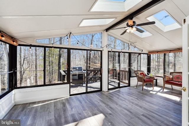 unfurnished sunroom featuring ceiling fan and vaulted ceiling with skylight