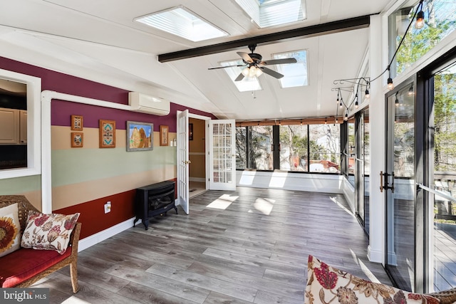 interior space with lofted ceiling with skylight, a ceiling fan, a wood stove, and a wall mounted AC