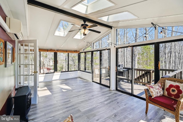 sunroom with vaulted ceiling with skylight, a ceiling fan, and a wall mounted AC