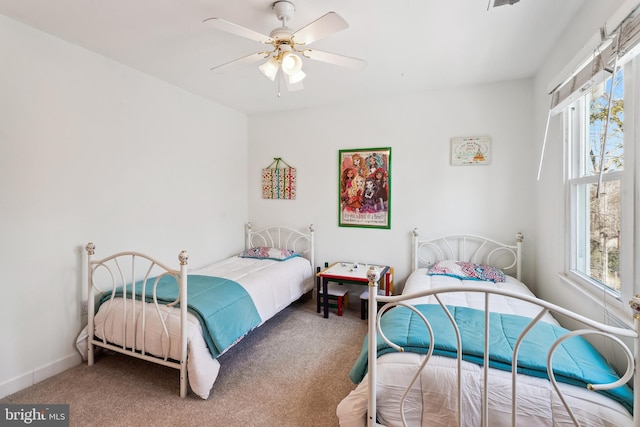 carpeted bedroom with ceiling fan, multiple windows, and baseboards