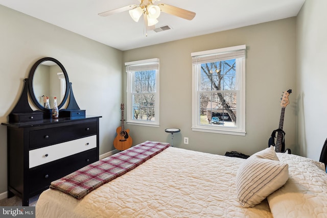 carpeted bedroom featuring ceiling fan, visible vents, and baseboards