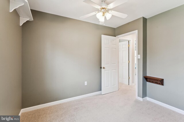 unfurnished room with a ceiling fan, light colored carpet, and baseboards