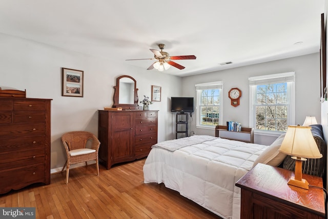 bedroom with light wood-style floors, ceiling fan, and visible vents