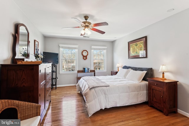 bedroom with light wood-style flooring, visible vents, baseboards, and a ceiling fan