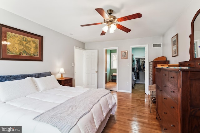 bedroom featuring baseboards, visible vents, a spacious closet, light wood-style floors, and a closet