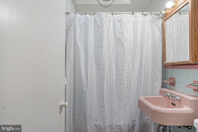 bathroom with tasteful backsplash, a shower with shower curtain, and a sink