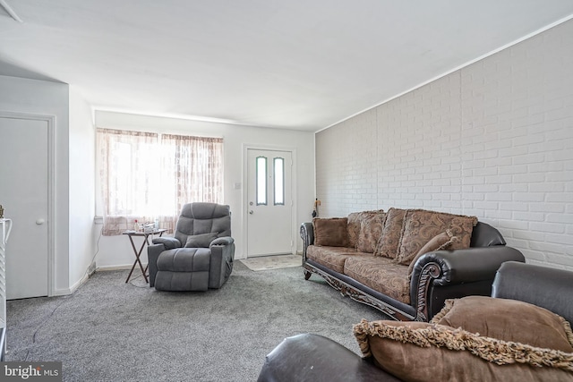 carpeted living room featuring baseboards and brick wall