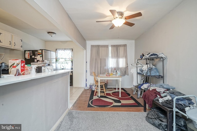 kitchen with light countertops, a ceiling fan, freestanding refrigerator, and light colored carpet