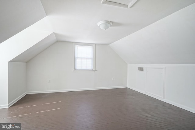 additional living space with dark wood-style floors, lofted ceiling, visible vents, and baseboards