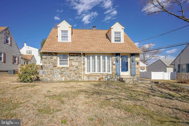 cape cod house with stone siding, a shingled roof, cooling unit, and fence