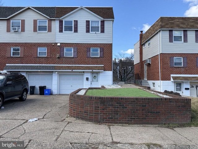 townhome / multi-family property featuring driveway, a front yard, a garage, and brick siding