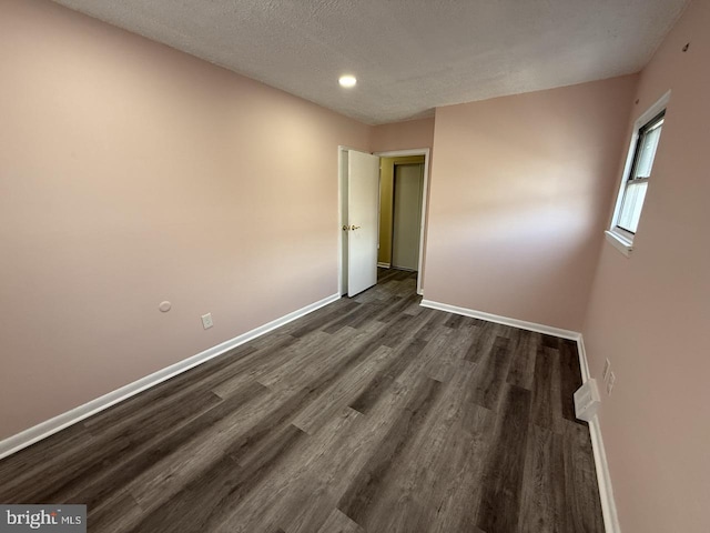 unfurnished bedroom featuring dark wood-style floors, a textured ceiling, and baseboards