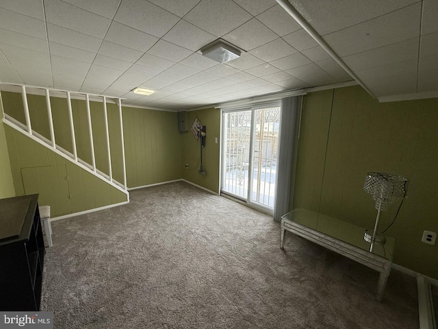 below grade area featuring carpet flooring, wood walls, and baseboards