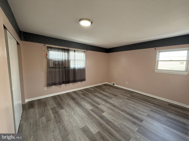 unfurnished room featuring visible vents, baseboards, and wood finished floors