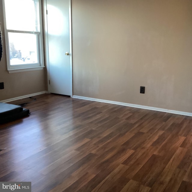 empty room with dark wood-style flooring and baseboards