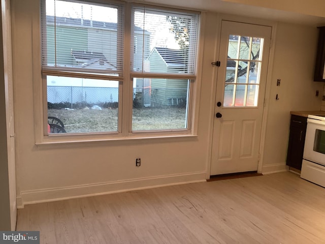 doorway featuring baseboards and light wood-style floors