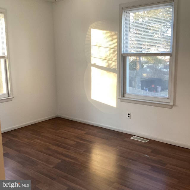 empty room featuring visible vents, baseboards, and wood finished floors