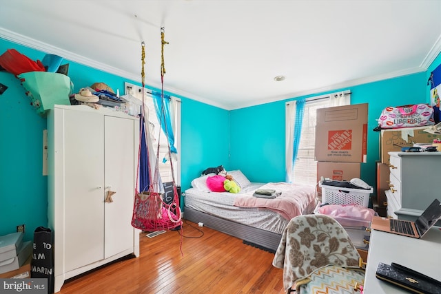 bedroom with crown molding and wood finished floors