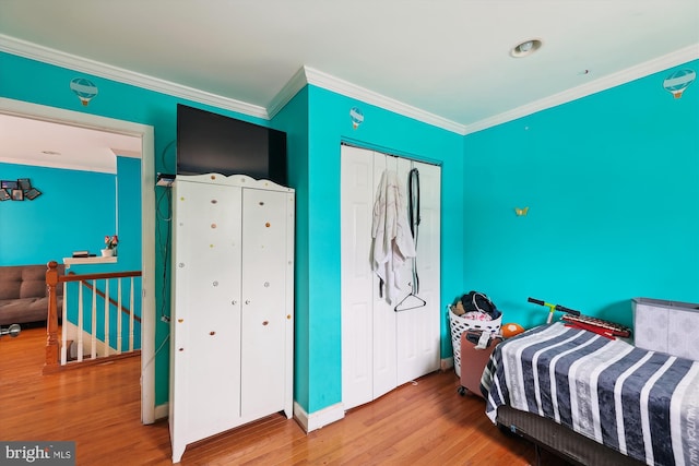 bedroom featuring ornamental molding, baseboards, a closet, and wood finished floors
