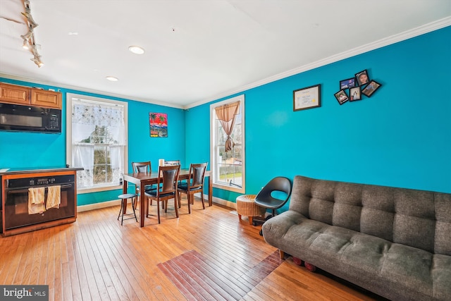 living room featuring baseboards, a wealth of natural light, light wood-style flooring, and ornamental molding