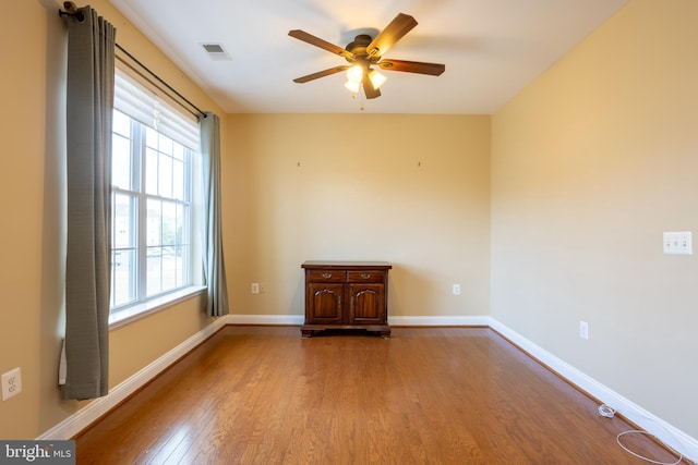 spare room with a ceiling fan, baseboards, visible vents, and wood finished floors