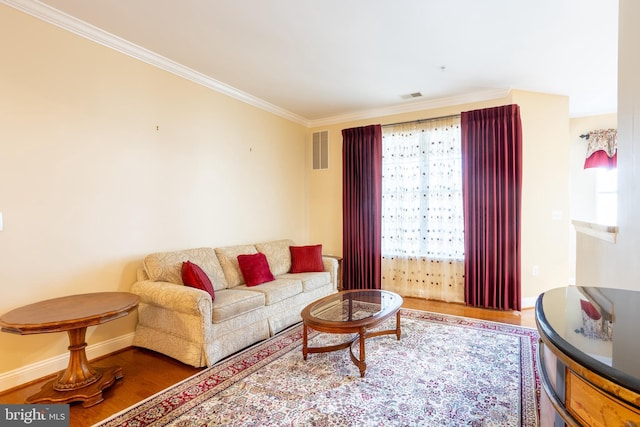 living area with visible vents, crown molding, baseboards, and wood finished floors