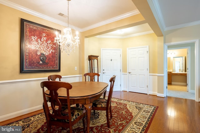 dining room with baseboards, visible vents, crown molding, and hardwood / wood-style floors