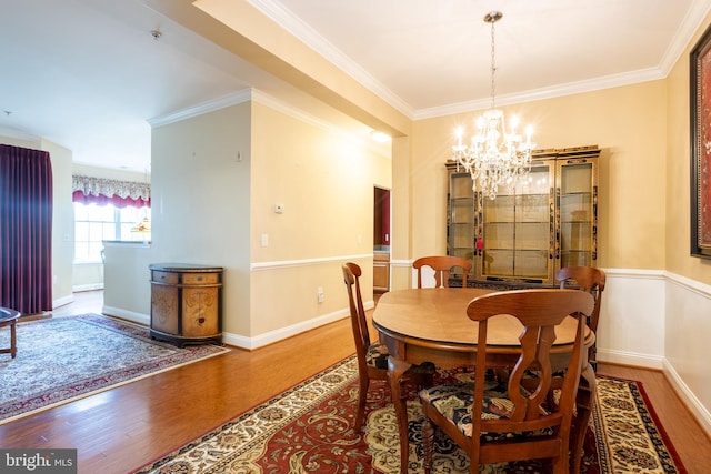 dining area with crown molding, baseboards, wood finished floors, and an inviting chandelier