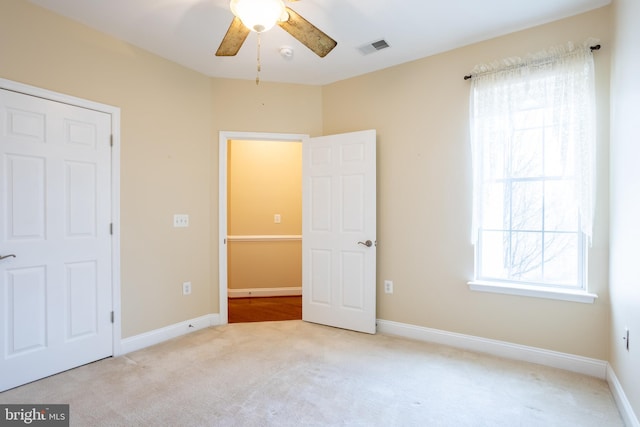 unfurnished bedroom with carpet floors, visible vents, baseboards, and a ceiling fan