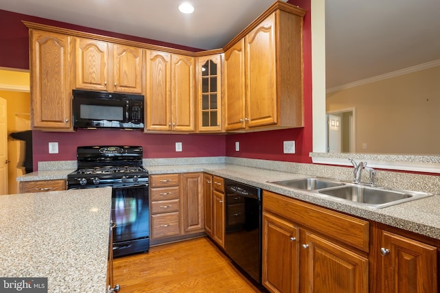 kitchen with a sink, light countertops, ornamental molding, light wood-type flooring, and black appliances