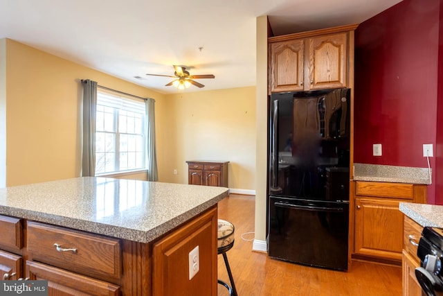 kitchen featuring range, brown cabinets, freestanding refrigerator, and light wood-style floors