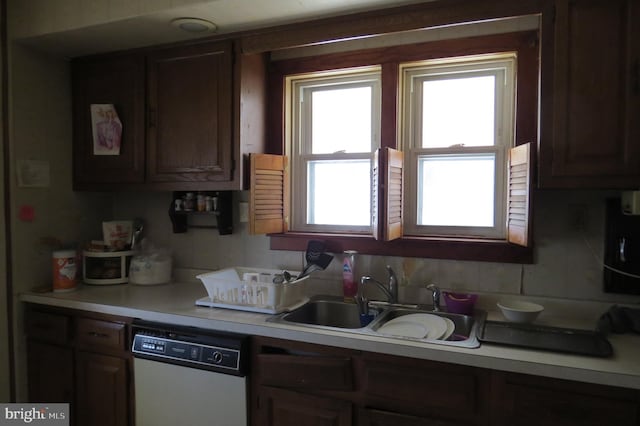 kitchen with light countertops, white dishwasher, and a sink