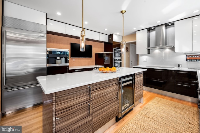 kitchen with beverage cooler, wall chimney exhaust hood, appliances with stainless steel finishes, and modern cabinets