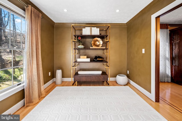 living area with light wood-style flooring, baseboards, and ornamental molding