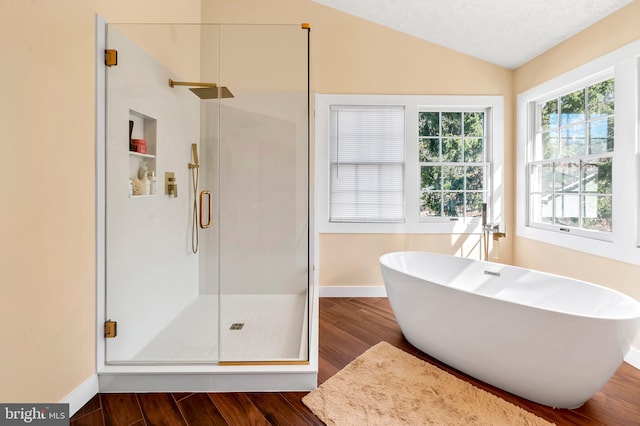 bathroom with a stall shower, baseboards, lofted ceiling, a soaking tub, and wood finished floors