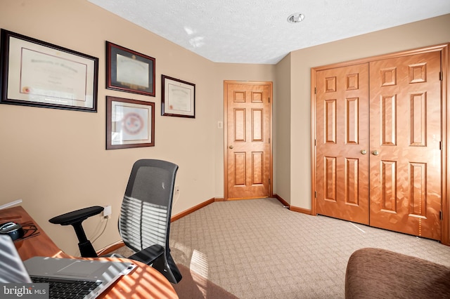 office area featuring light carpet, a textured ceiling, and baseboards