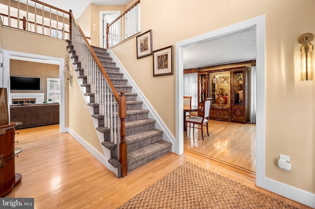 stairs featuring a high ceiling, baseboards, and wood finished floors