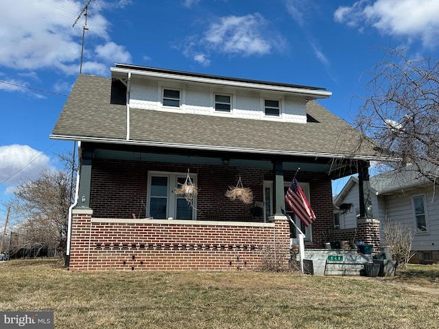 bungalow-style house with covered porch, brick siding, a front yard, and a shingled roof