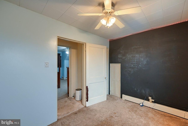unfurnished bedroom featuring a ceiling fan, baseboard heating, and light carpet
