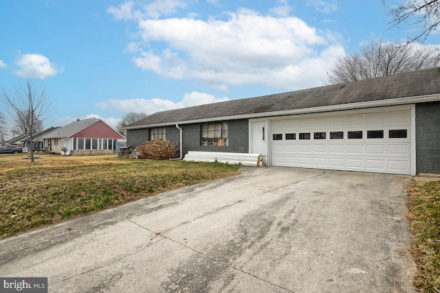 ranch-style house featuring a garage, concrete block siding, concrete driveway, and a front lawn