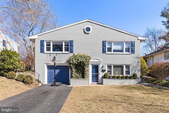 traditional-style house featuring an attached garage, brick siding, aphalt driveway, and a front yard