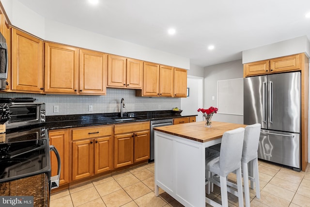 kitchen with light tile patterned floors, a toaster, tasteful backsplash, appliances with stainless steel finishes, and a sink