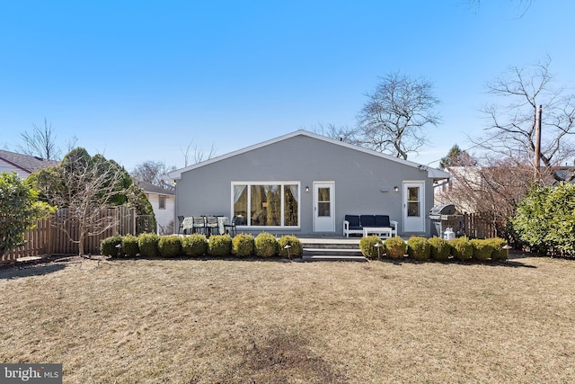 back of property with fence, an outdoor hangout area, and a lawn