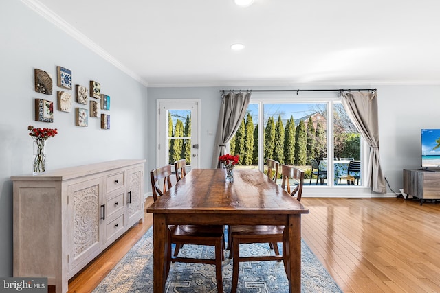 dining room with ornamental molding and light wood-style flooring